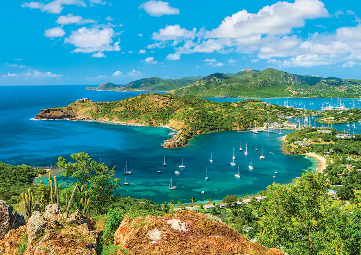 A view of a tropical island with sailboats in the water.